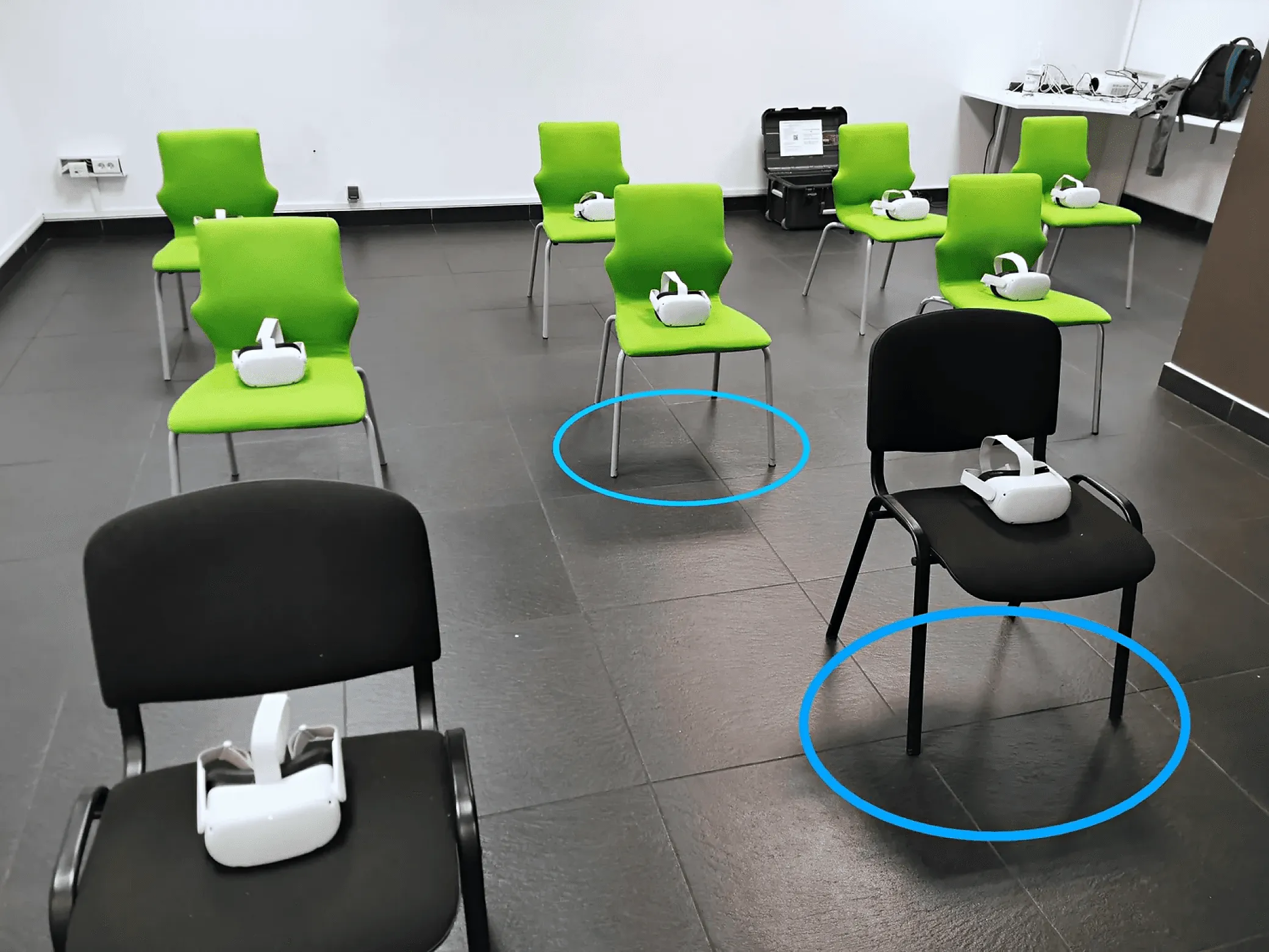 Chairs arranged in a training room with a VR headset on each, and blue circles marking each participant’s stationary boundary
