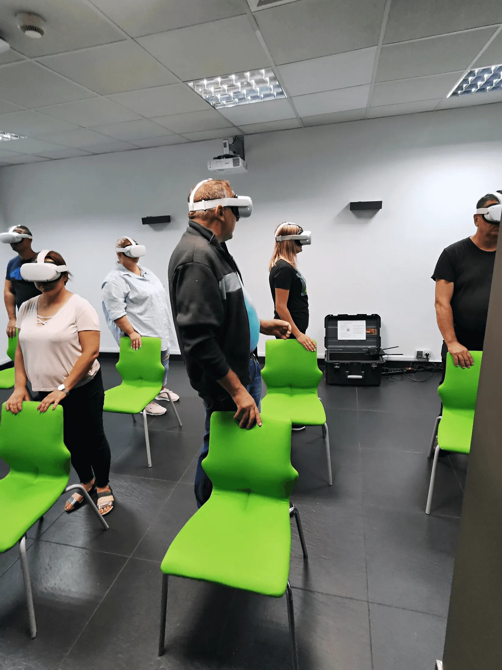 Participants in VR headsets standing next to chairs during group training