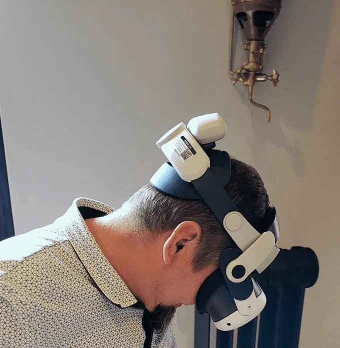A man wearing a Meta Quest headset with a battery strap at the back of his head