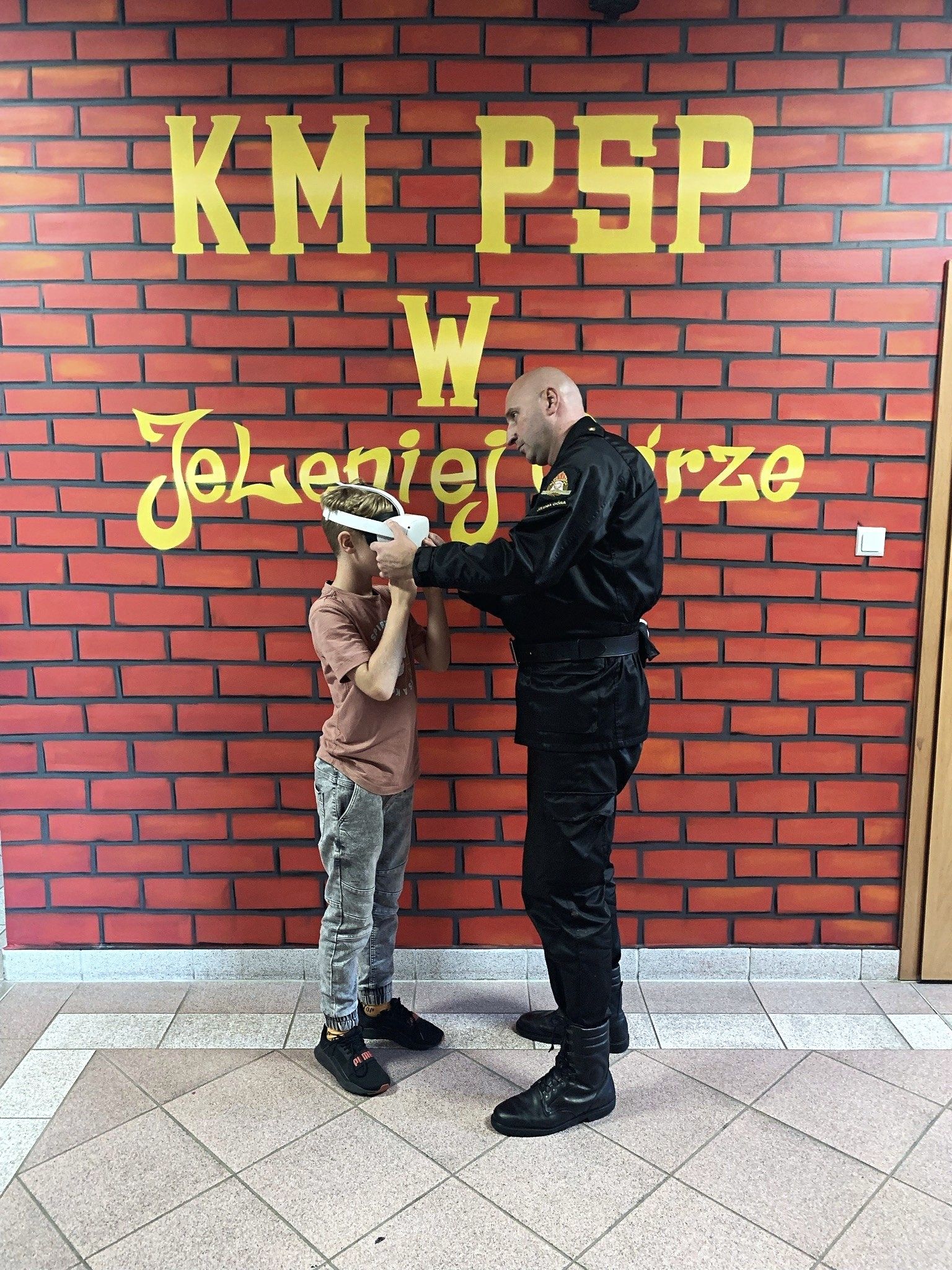 A firefighter putting a VR headset on a child during a training session