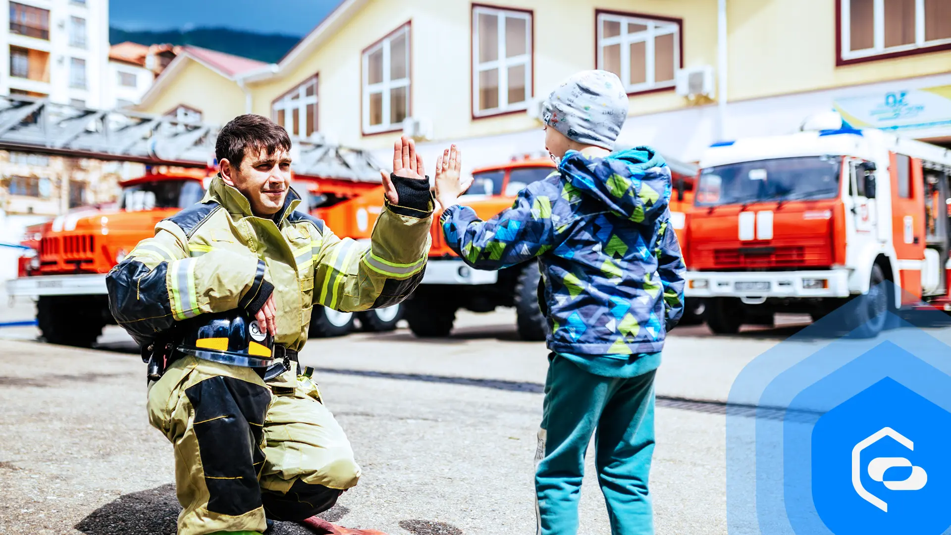 A firefighter high-fives a child in front of fire engines
