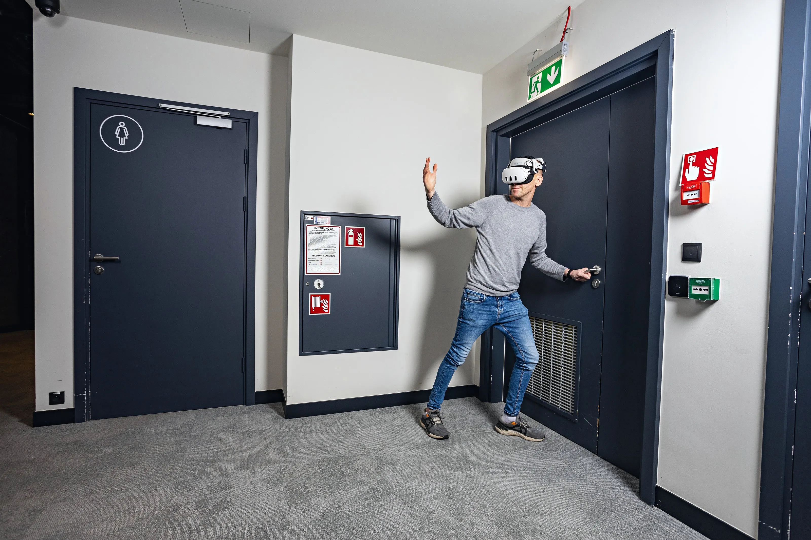 Employee in a VR headset practising in an office corridor next to fire safety signs