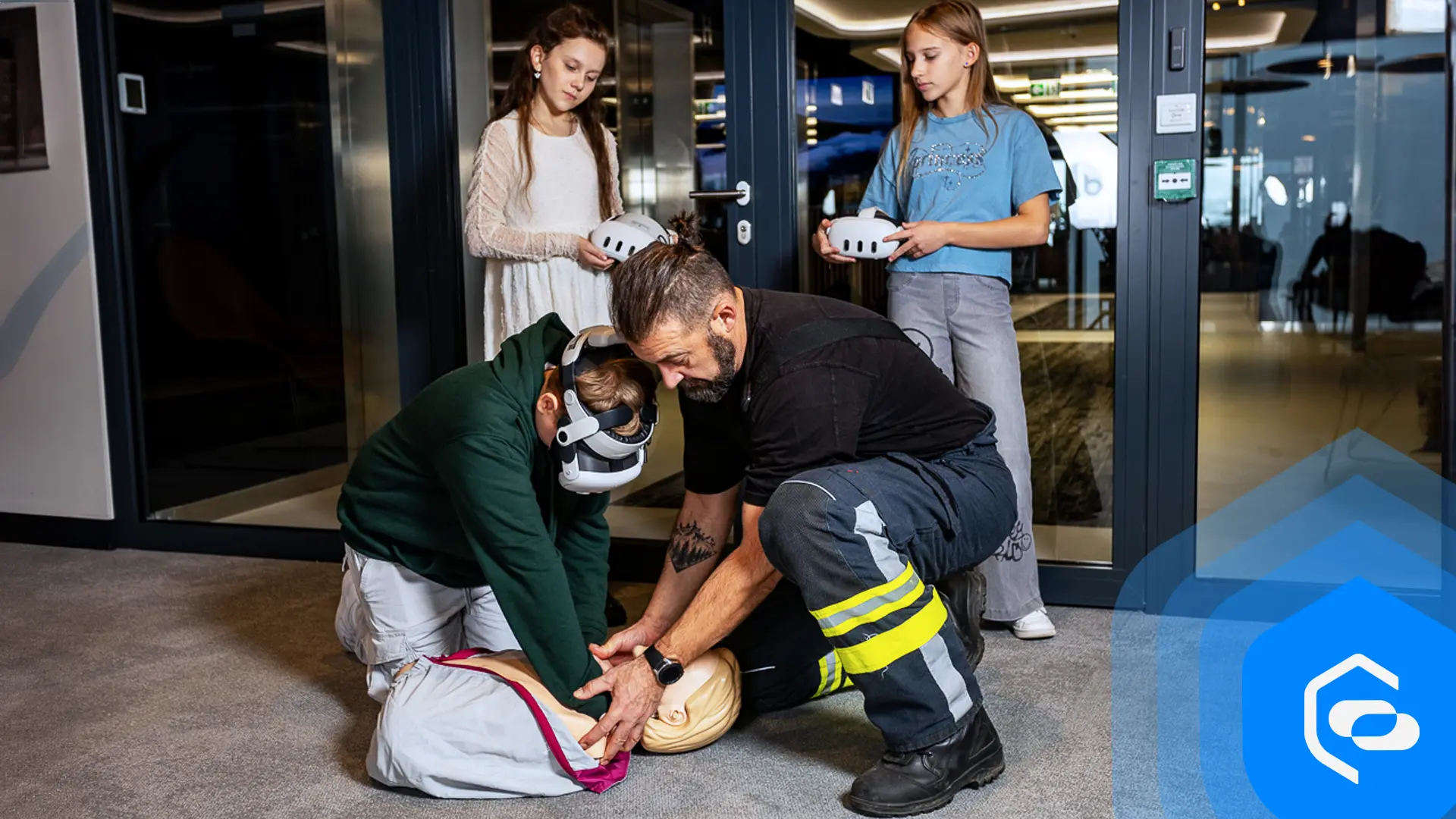 A firefighter shows two girls with VR headsets how to perform resuscitation on a manikin