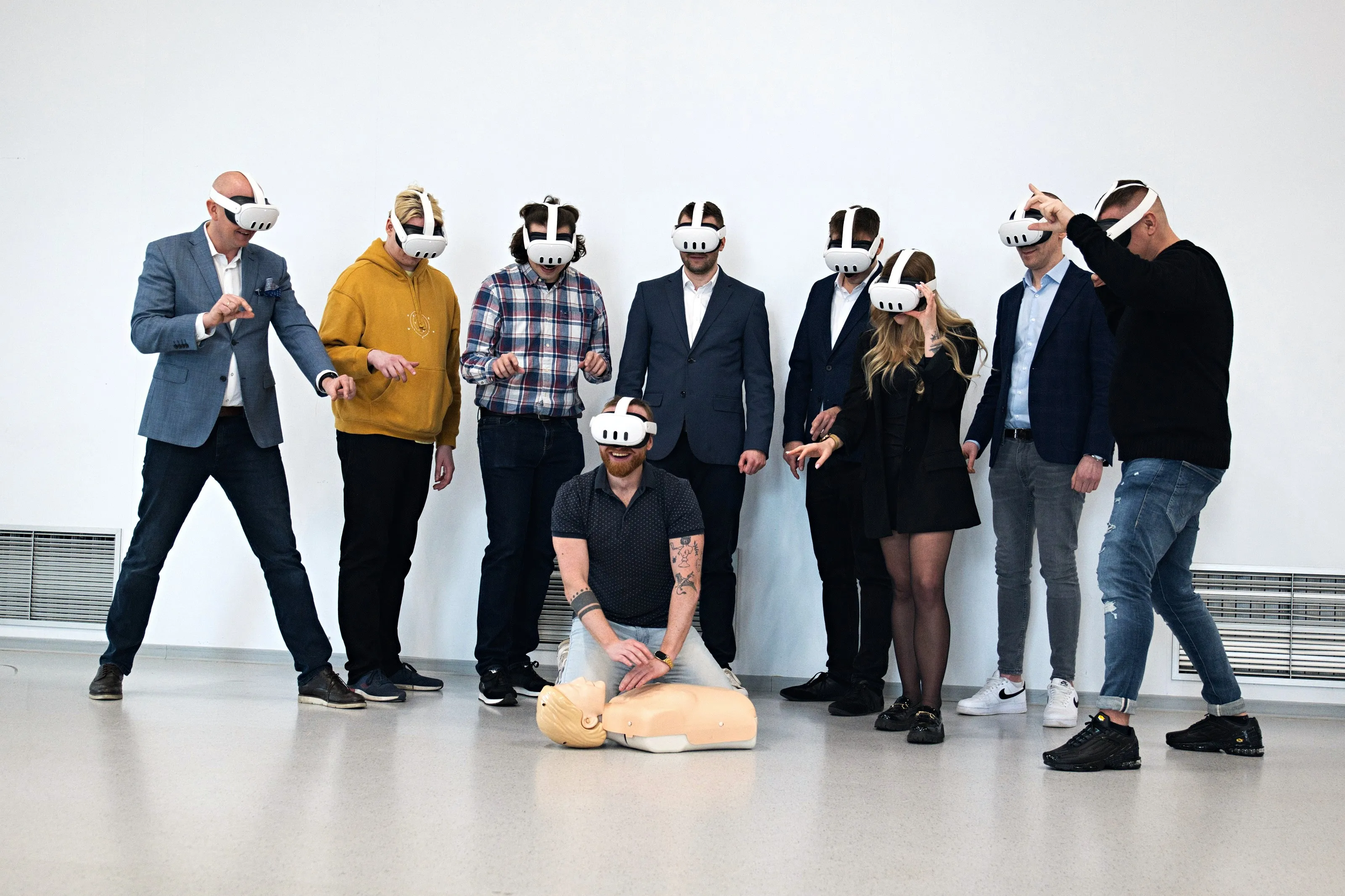 A group of employees in VR headsets at a safety training event, one of them practising CPR on a mannequin