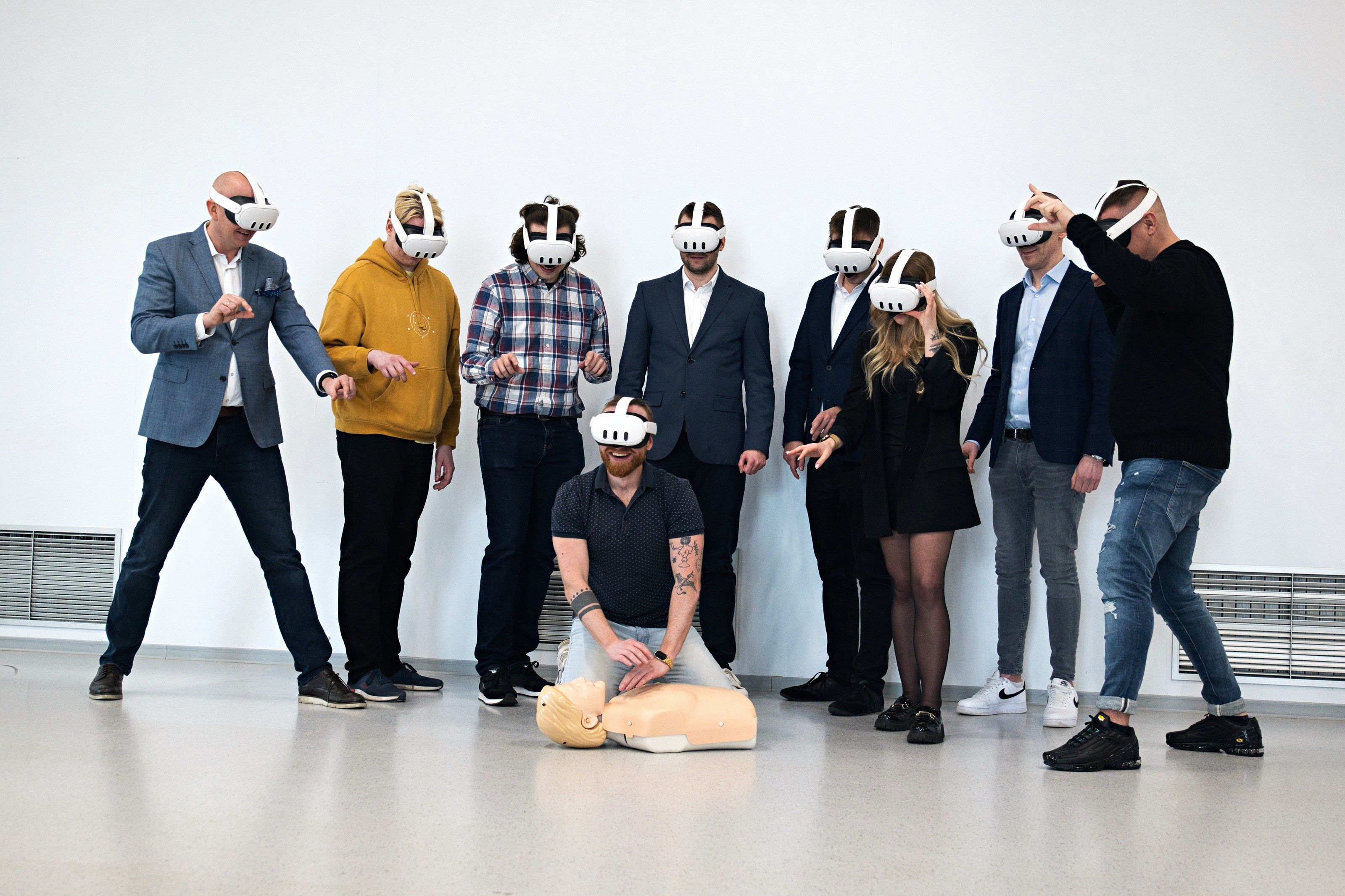A group of employees in VR headsets at a safety training event, one of them practising CPR on a mannequin