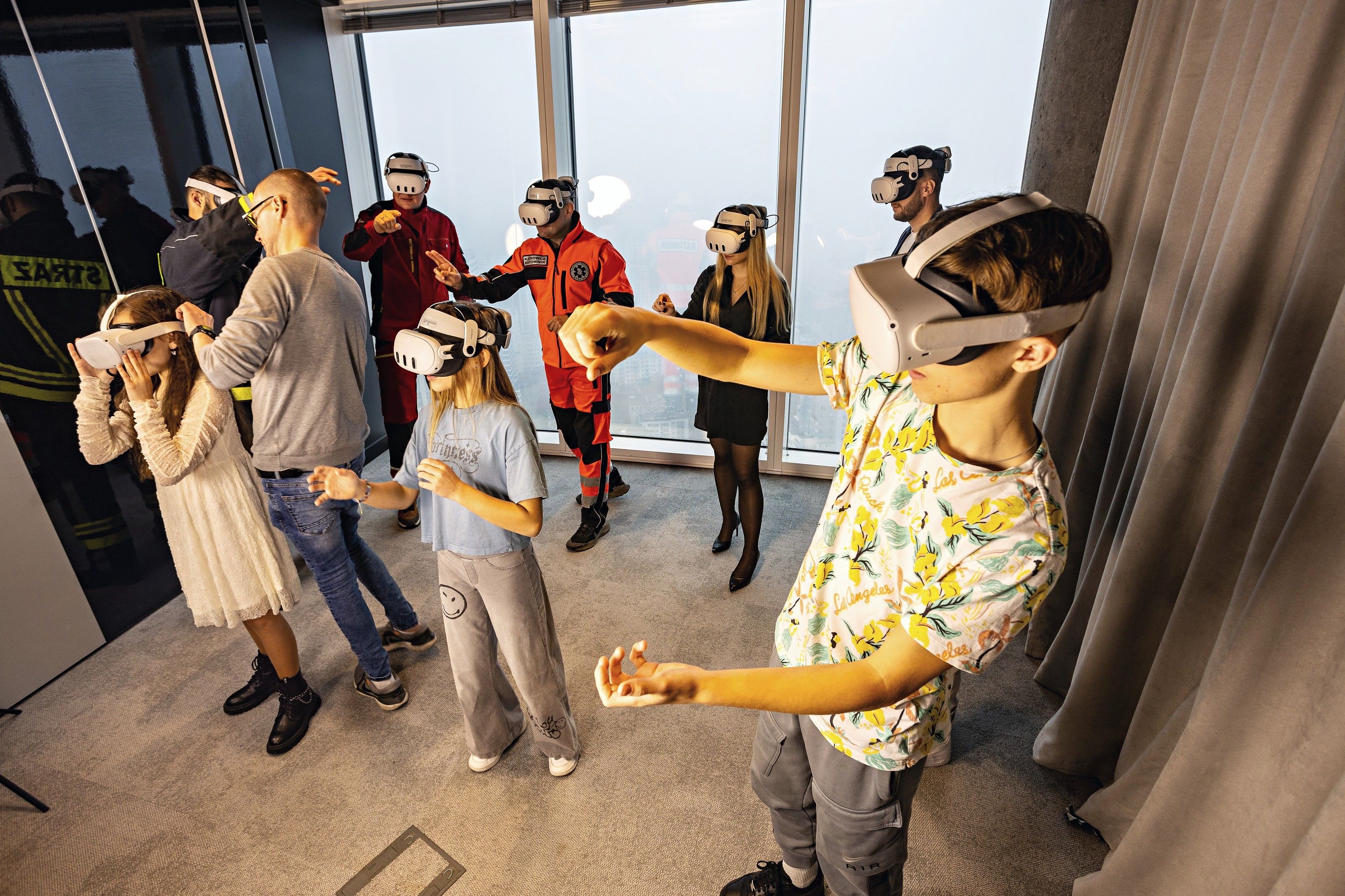 Children and adults try VR safety scenarios together, with firefighters and paramedics in the background