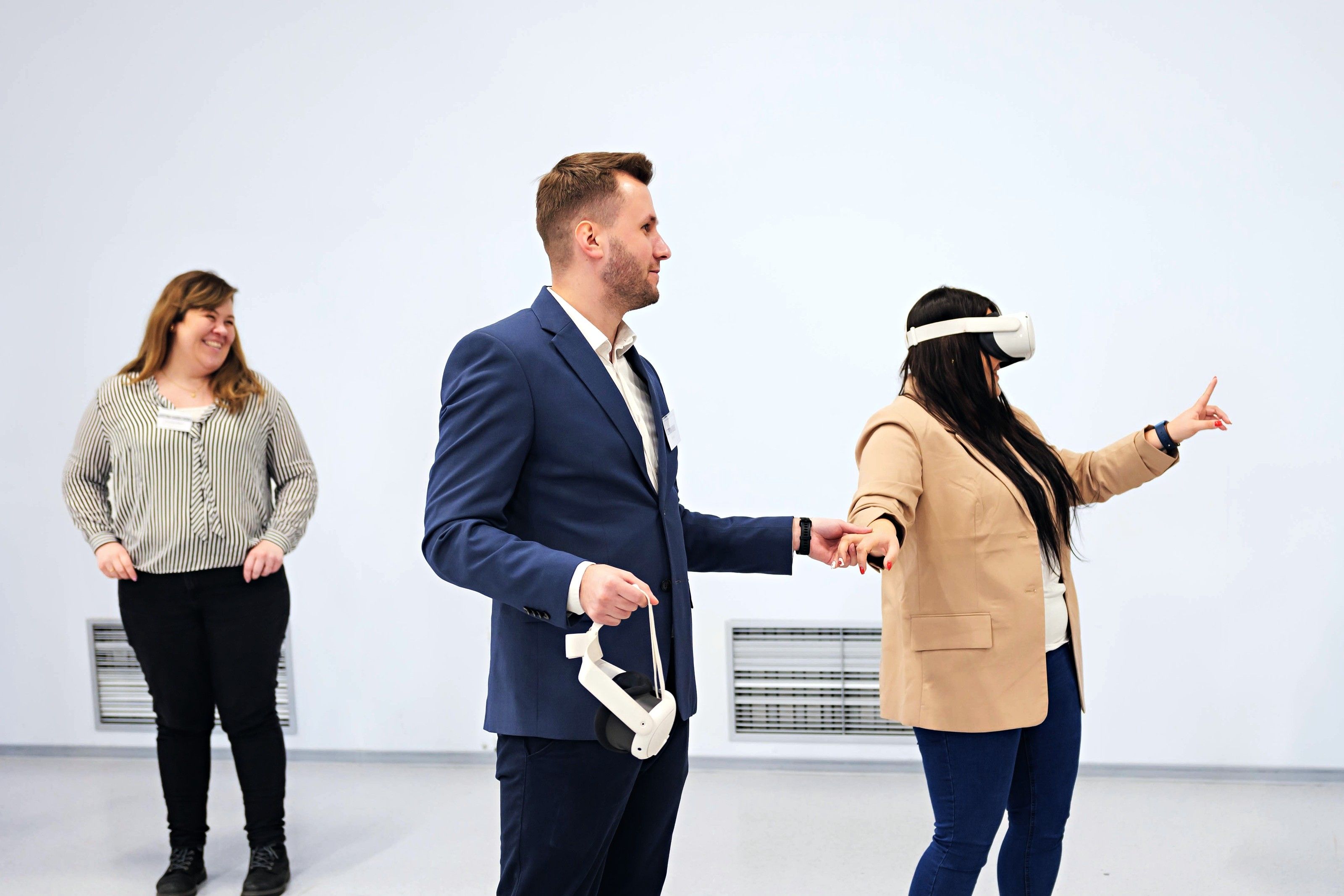 A trainer guides a participant in a VR headset while another participant watches