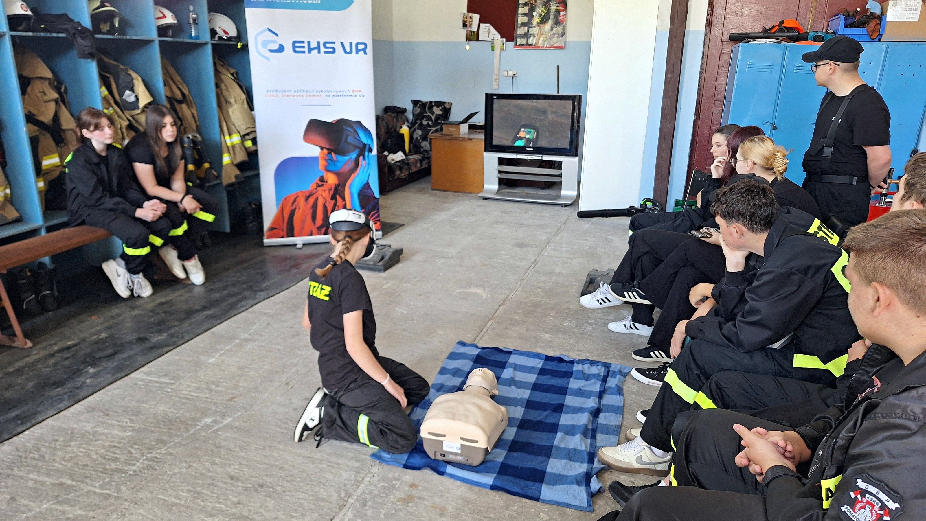 A young volunteer firefighter practises CPR on a mannequin while her team watches in the fire station